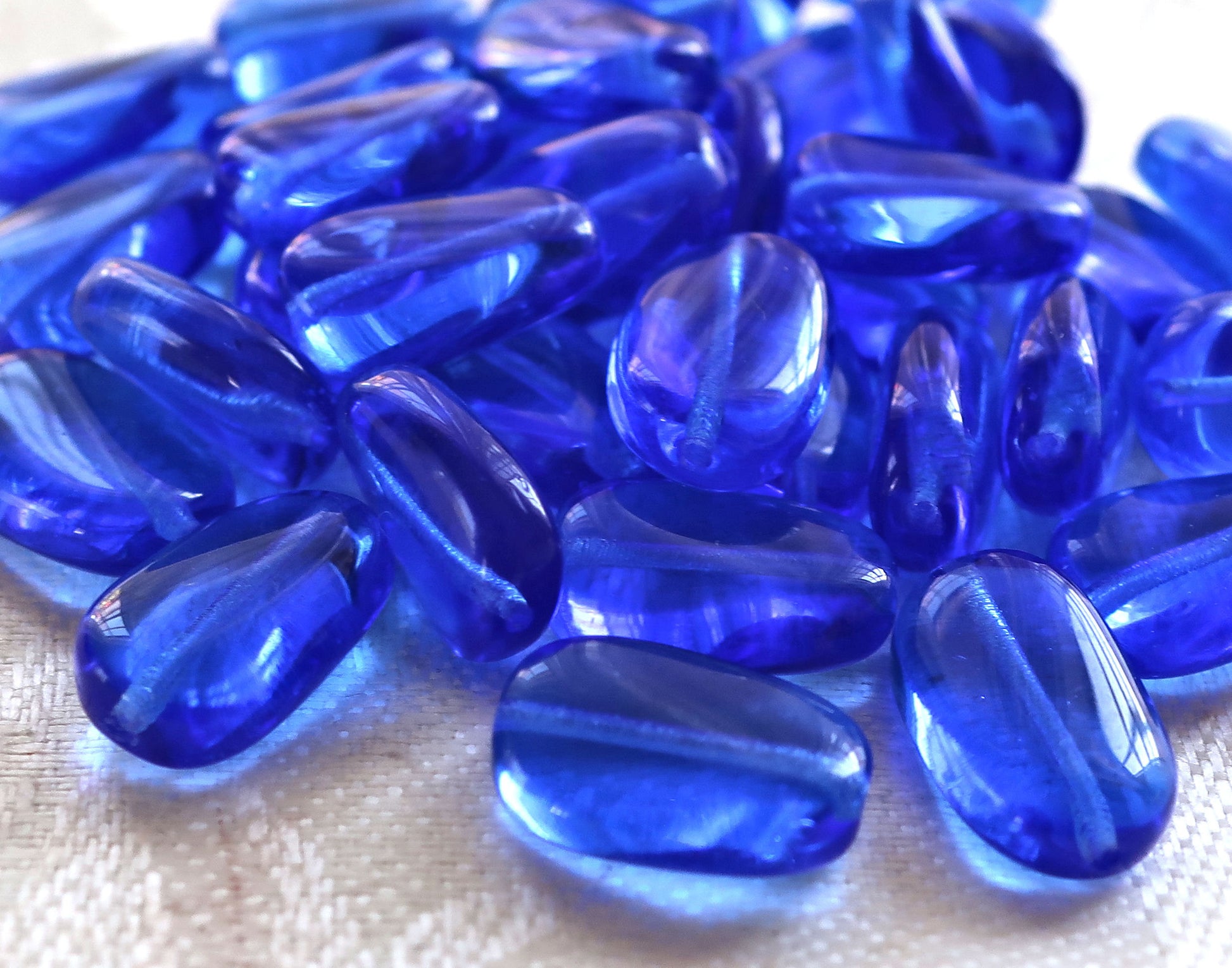 Lot of 25 transparent Sapphire Blue slightly twisted oval Czech Glass beads, 14mm x 8mm pressed glass beads C7325 - Glorious Glass Beads
