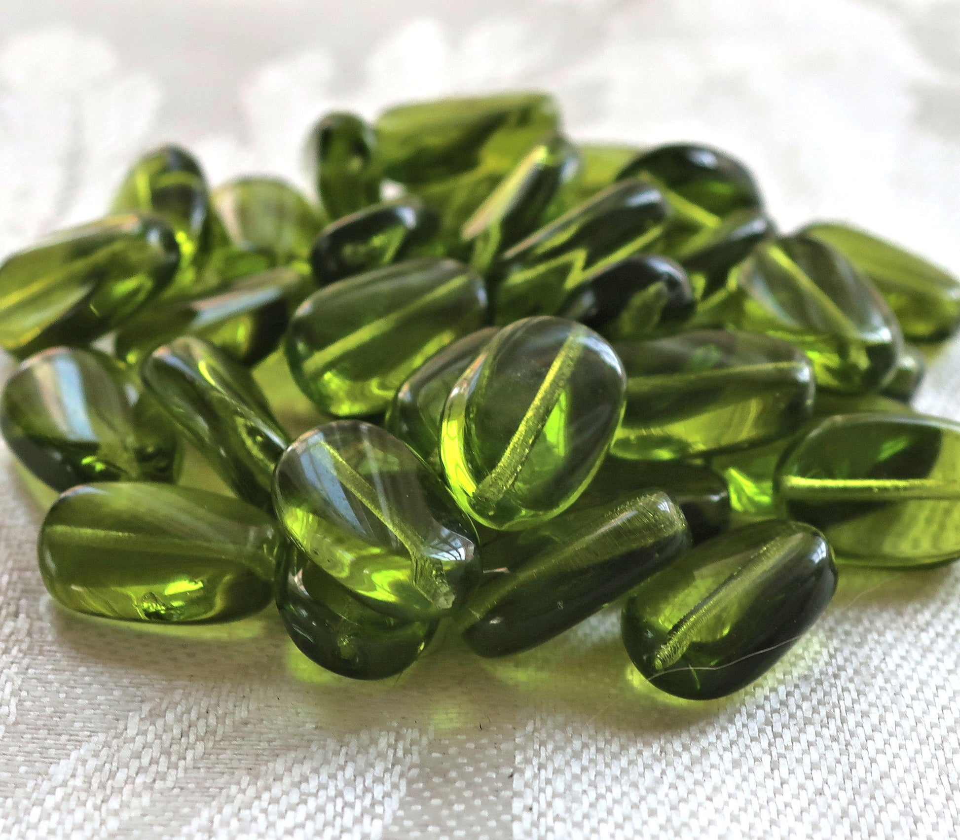 Lot of 25 transparent Olivine, Olive Green slightly twisted oval Czech Glass beads, 14mm x 8mm pressed glass beads C2925 - Glorious Glass Beads